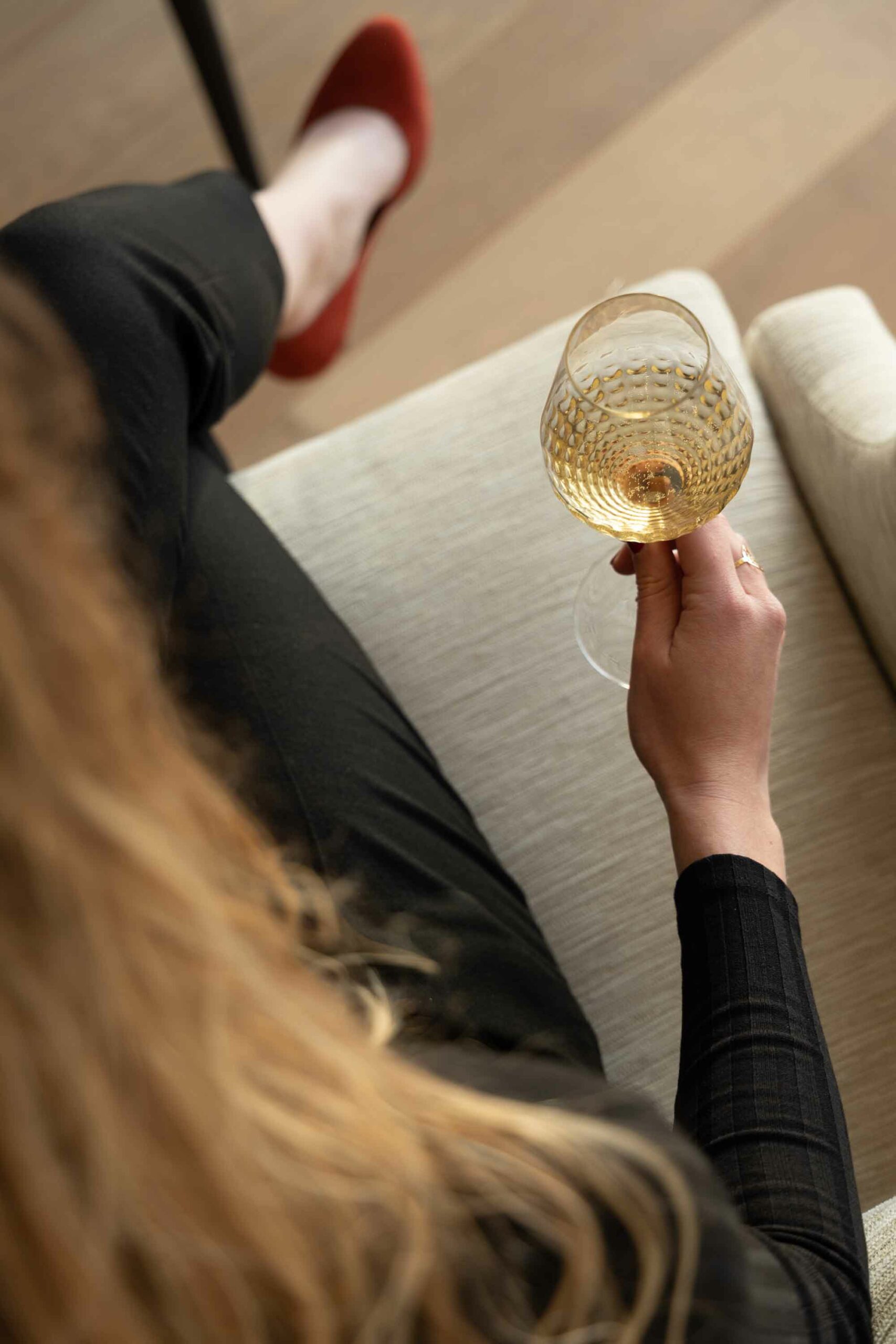 Une femme est assise dans un fauteil du Royal Champagne avec une coupe de la cuvée Chronothèque Palmes d'Or Champagne Nicolas Feuillatte | Réalisation Agence de communication Discovery