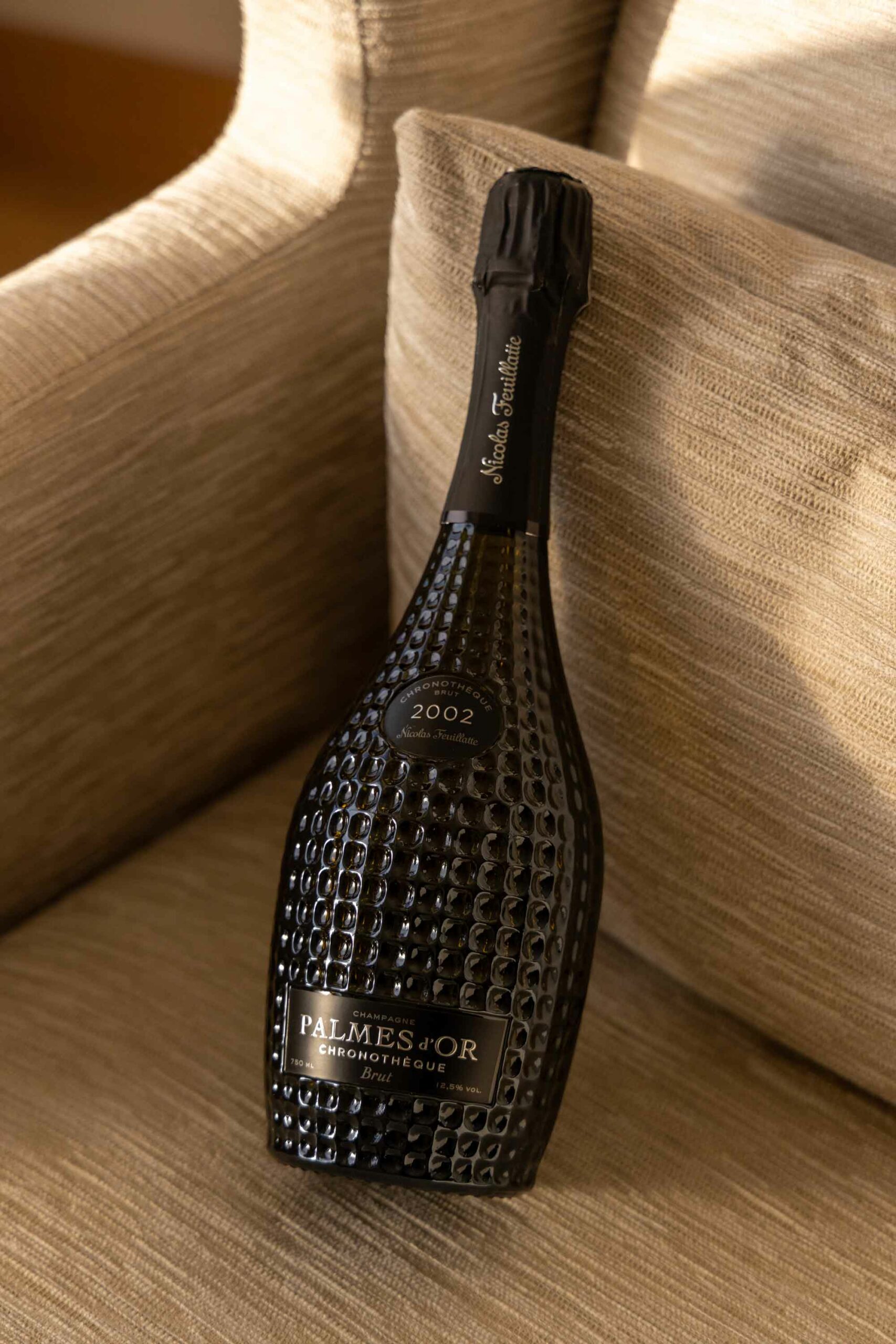 Une bouteille de la cuvée Chronothèque Palmes d'Or Champagne Nicolas Feuillatte dans une fauteil du Royal Champagne | Réalisation Agence de communication Discovery