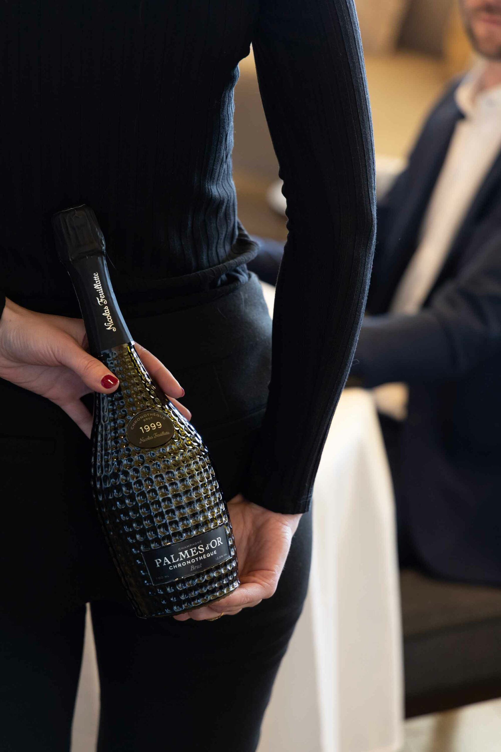 Une femme cache une Cuvée Chronothèque Palmes d'Or Champagne Nicolas Feuillatte dans son dos | Réalisation Agence de communication Discovery